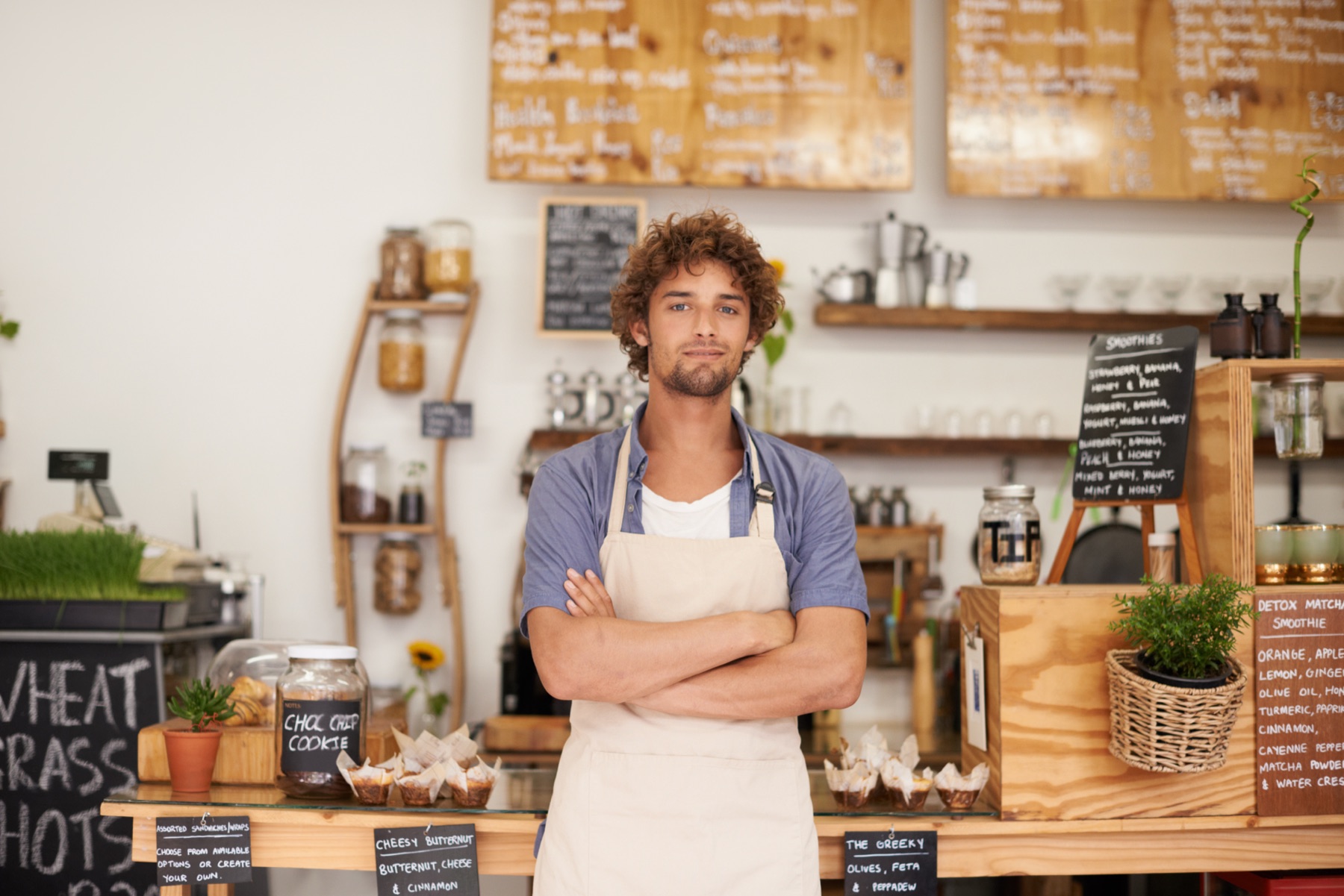 Commerçant en tablier derrière le comptoir de sa boutique.